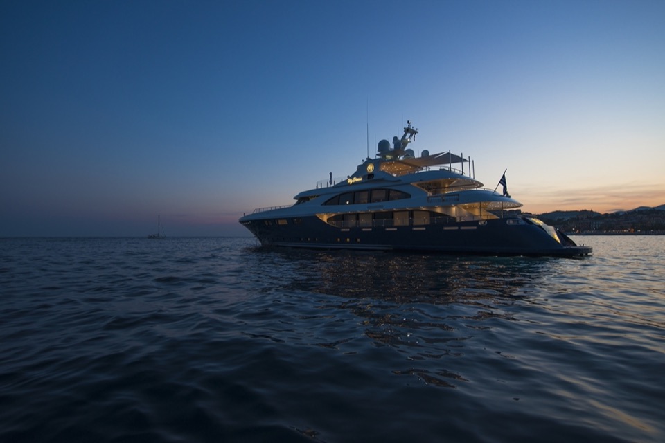 M/Y My Dream at anchor at dusk, her lights on under a sunset sky